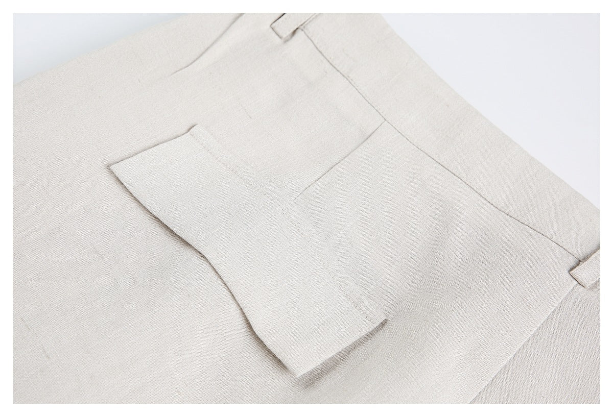 Close-up of a rectangular pocket and belt loop on light beige trousers.
