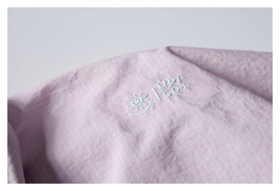 Close-up of a pale pink garment with a small embroidered sun and “UPF 50+” marking.