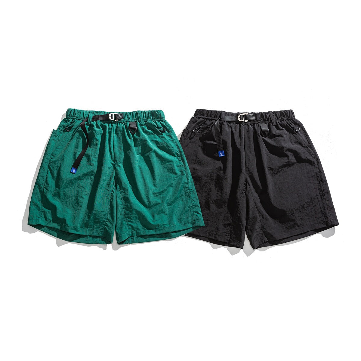 Front view of casual shorts in teal and black, with elastic waistbands, straps, clips and side pockets.