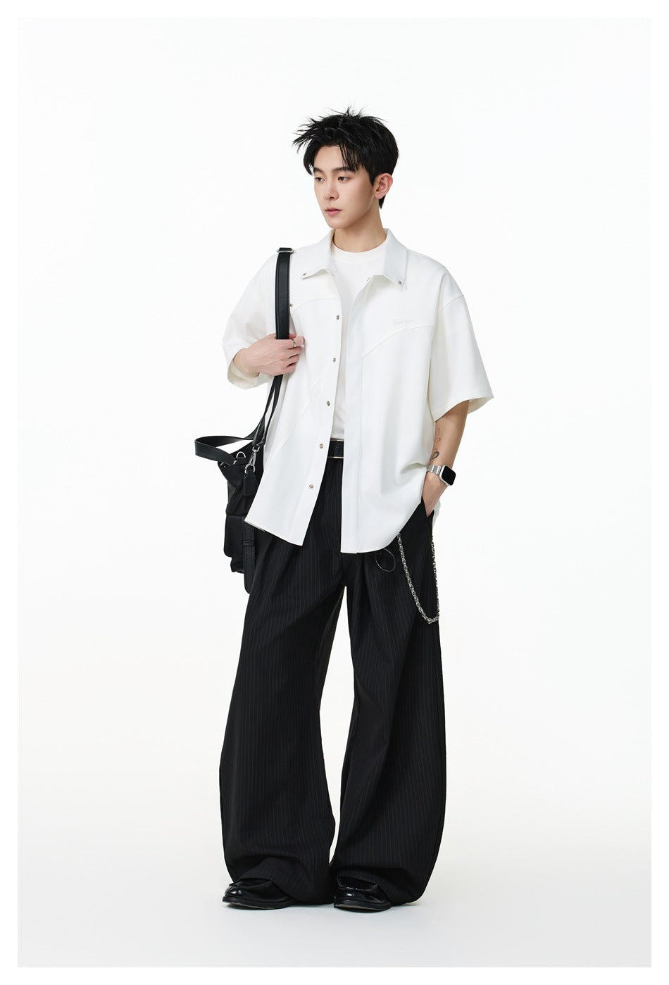 Full-length model wearing an oversized white short-sleeve button-up shirt and black wide-leg pinstripe trousers.