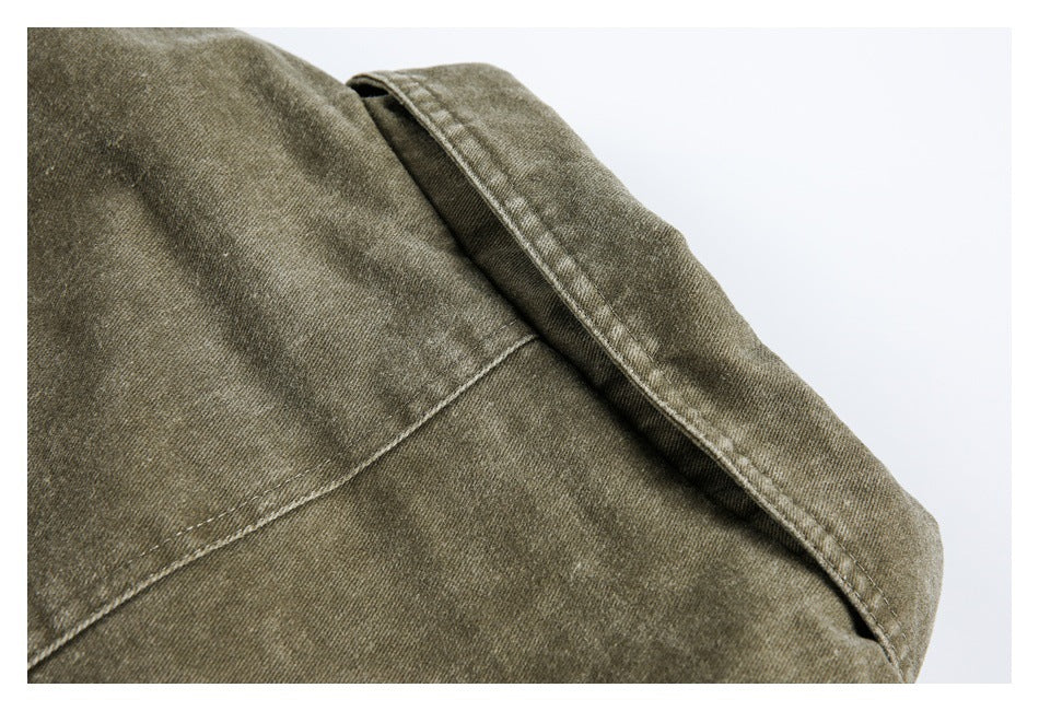 Close-up of an olive-brown jacket panel with a curved stitched seam and folded edge.