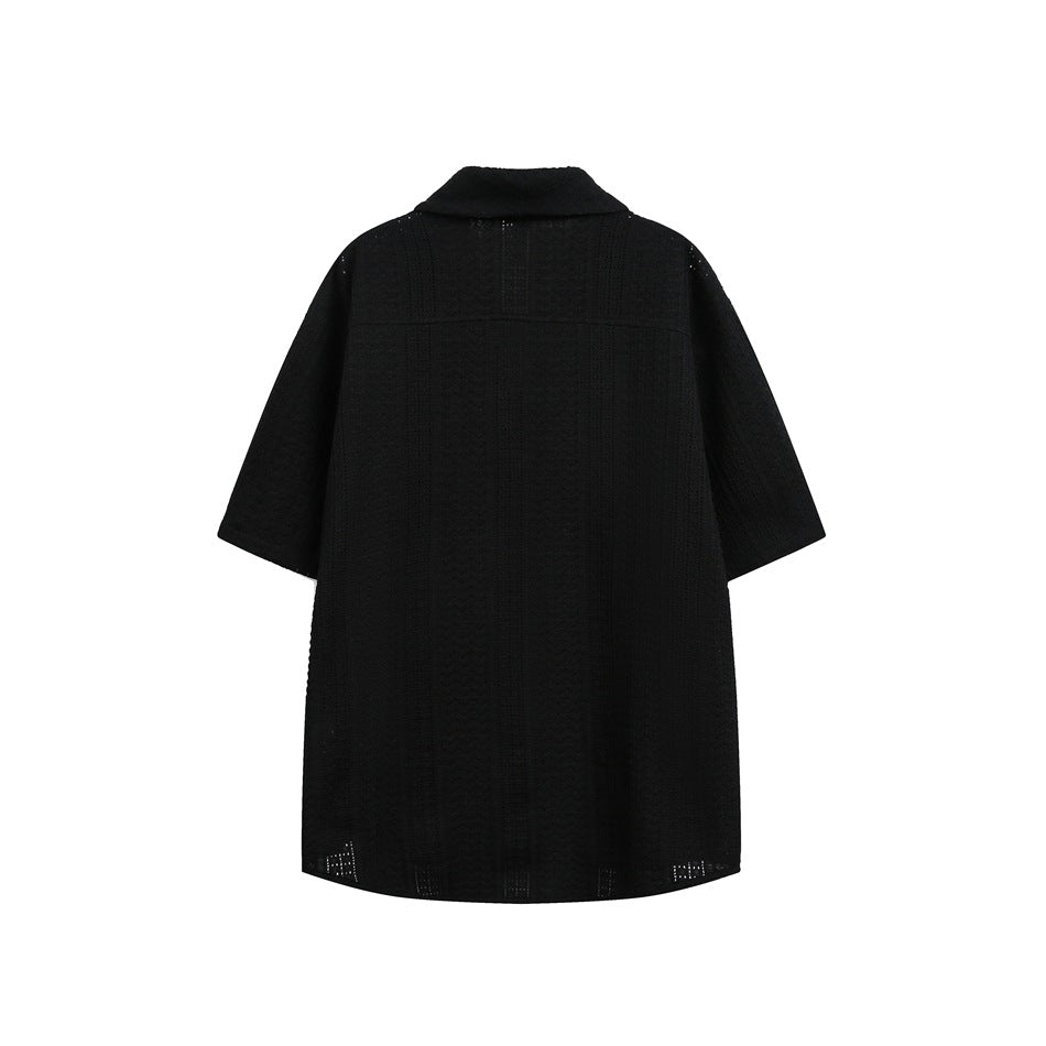 Back view of a black short-sleeve collared tunic with vertical textured panels, shown flat against a white background.
