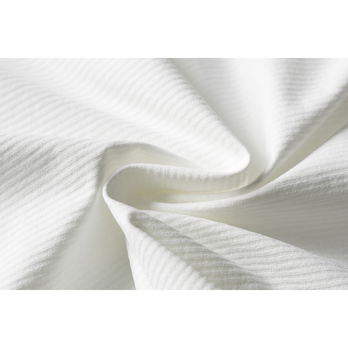 Close-up of white shirt fabric gathered to show its subtle ridged texture.