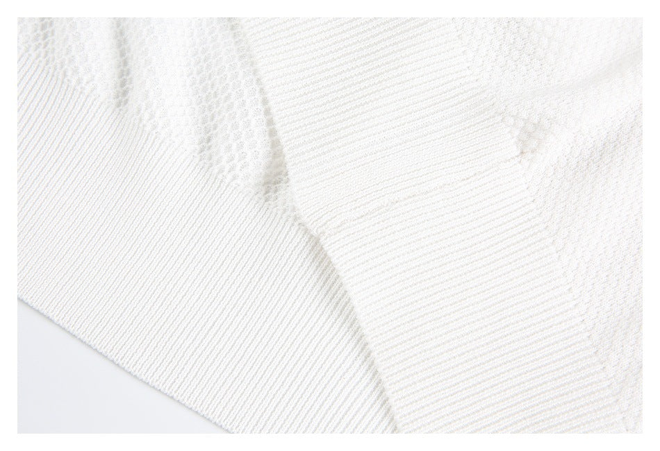 Close-up of a white knit garment seam joining textured fabric and ribbed trim.