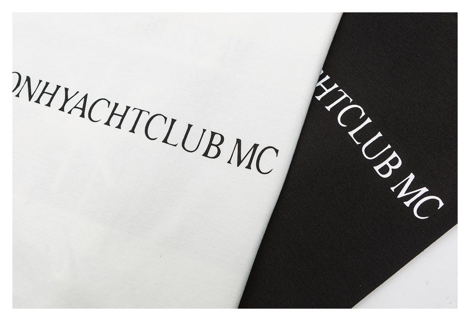 Close-up of printed lettering on overlapping off-white and black T-shirts.