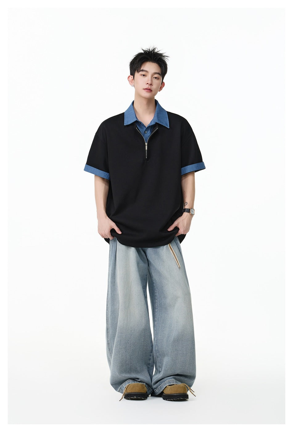 Model wearing the black half-zip polo top with blue collar and cuffs, front view with wide light-wash jeans