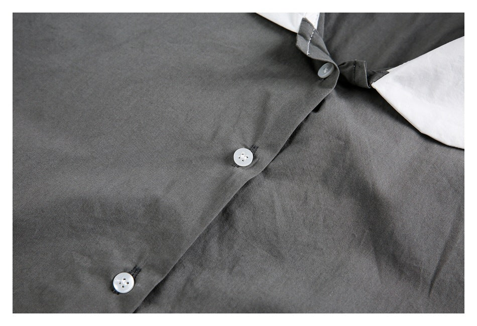 Close-up of the charcoal gray shirt front, showing its diagonal button placket and white buttons.