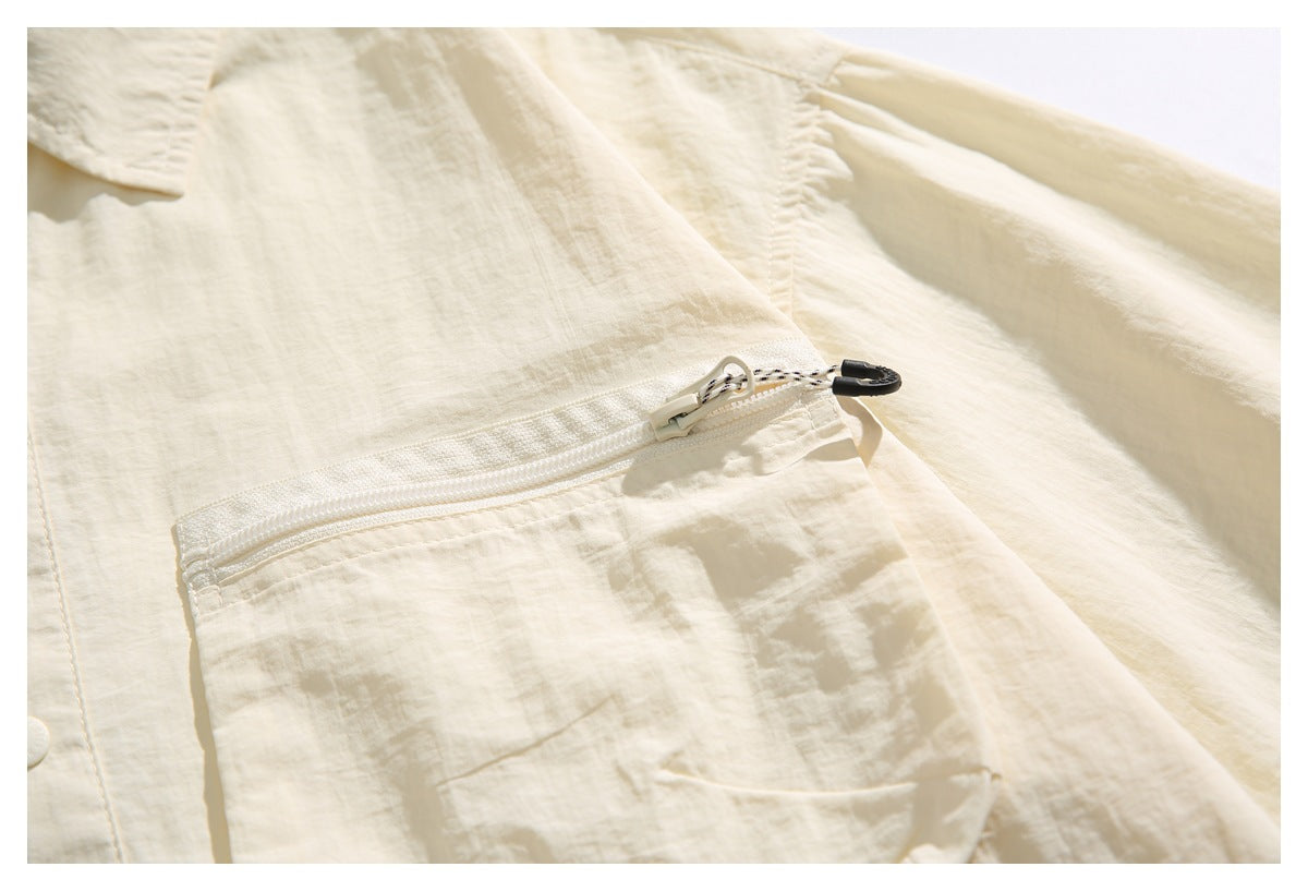 Close-up of an ivory shirt's zippered chest pocket, with a small lower pocket detail.
