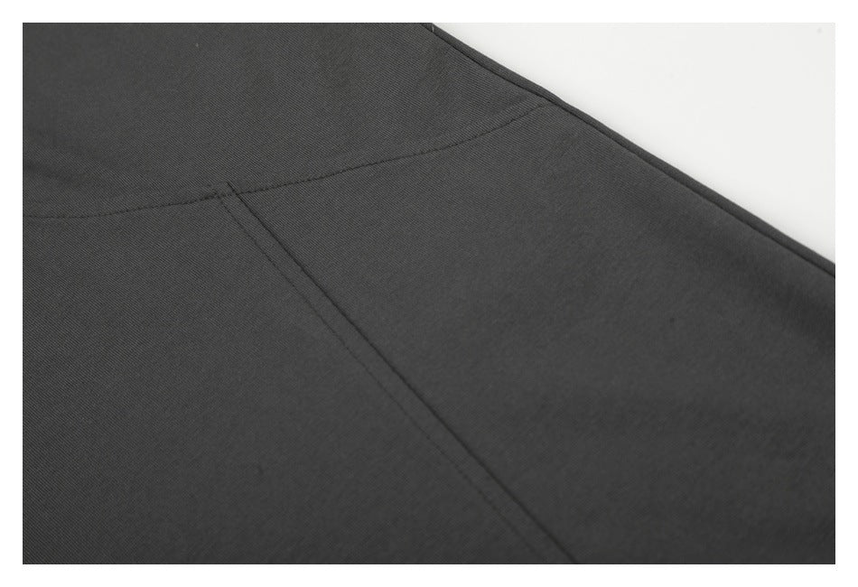 Close-up of charcoal T-shirt fabric and intersecting garment seams.