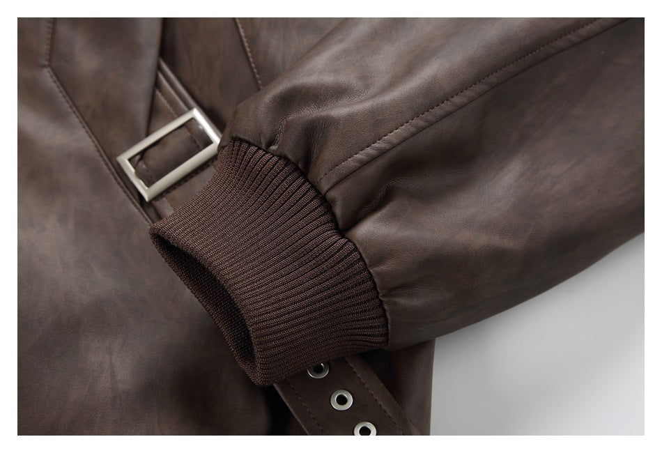 Close-up of the jacket's brown ribbed cuff beside a buckle strap and sleeve seam.