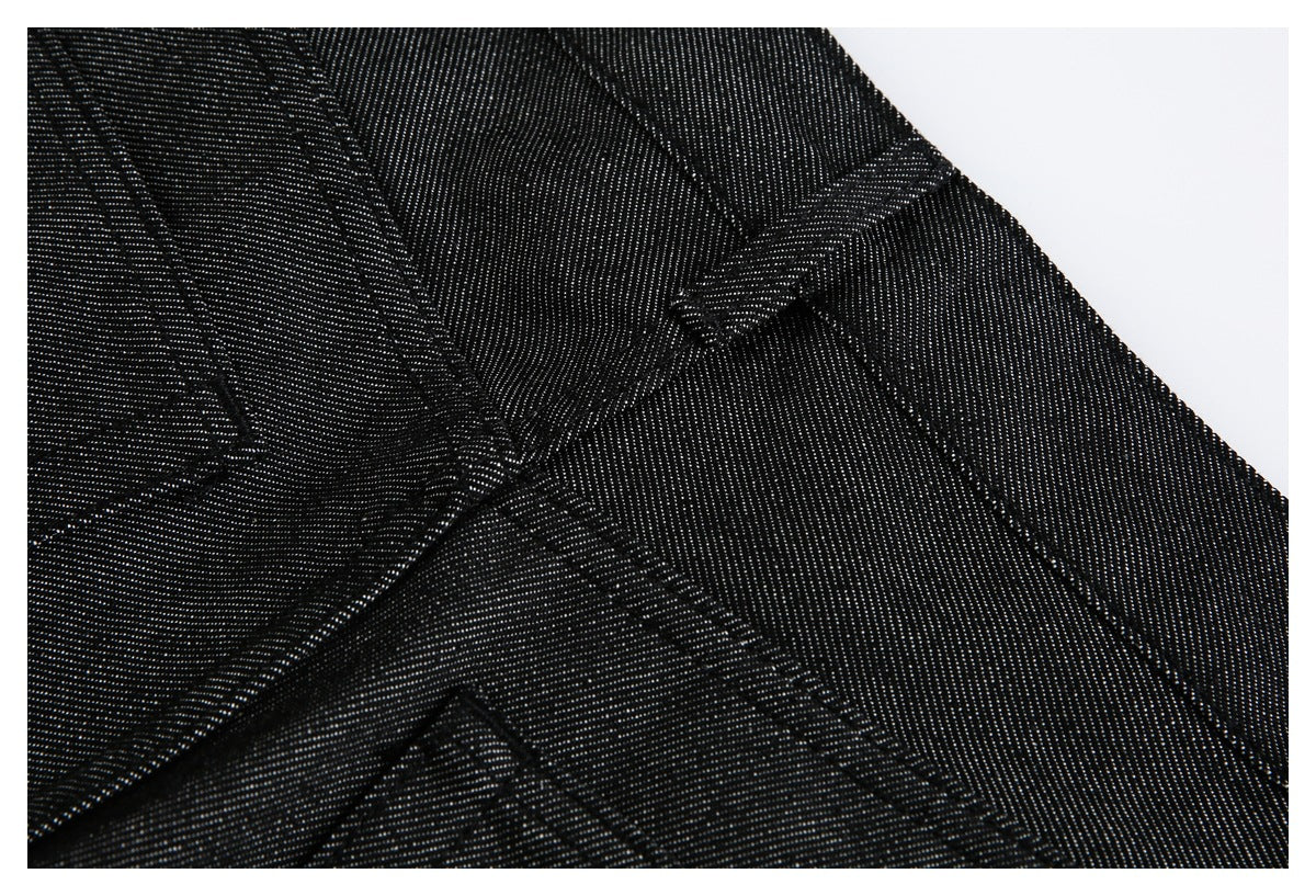 Close-up of black denim trousers showing the waistband, belt loop, and intersecting seams.