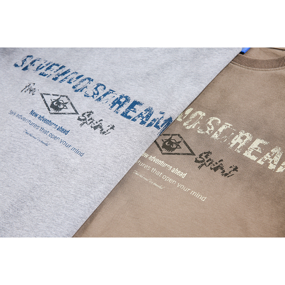 Close-up of distressed graphic prints on light gray and taupe T-shirts.