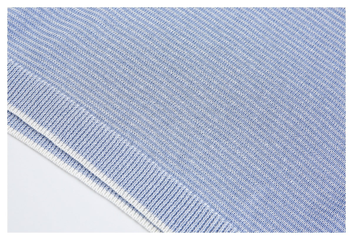 Close-up of the light blue knit sweater's ribbed hem with a narrow white edge.