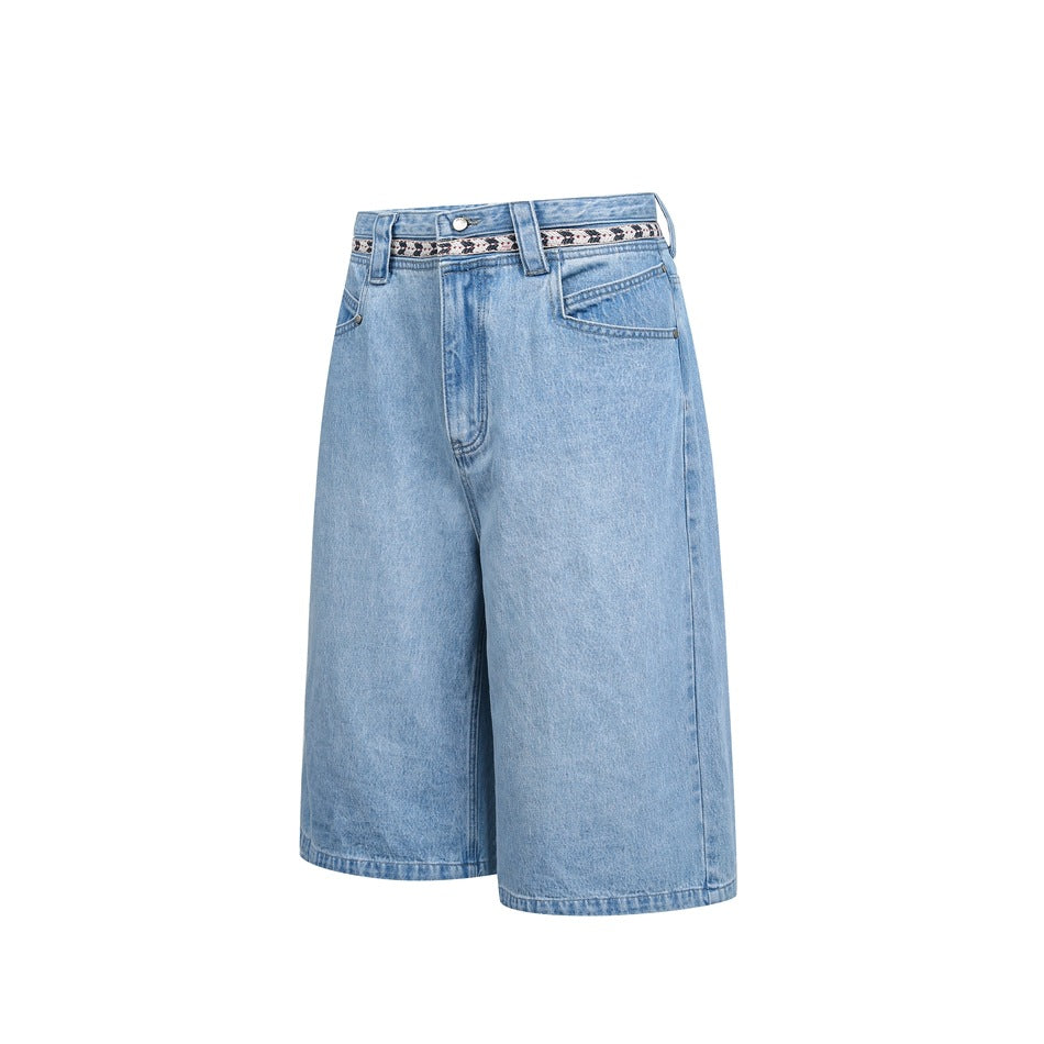 Front view of light blue denim knee-length shorts with wide legs, front pockets, and a patterned waistband.