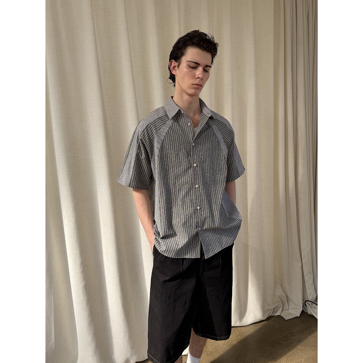 Model wearing a gray striped short-sleeve button-up shirt with contrasting raglan panels.