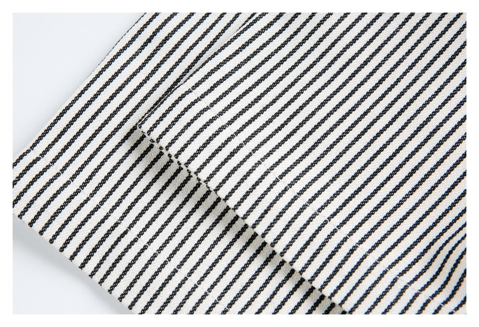 Close-up of cream fabric with narrow black stripes and a diagonal stitched seam.