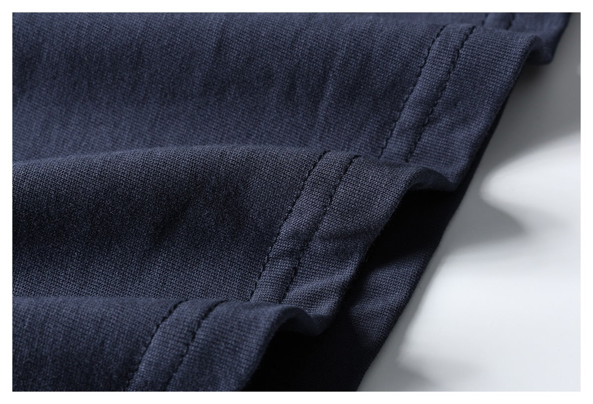 Close-up of a dark navy garment's folded hem with parallel rows of stitching.
