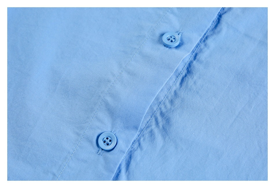 Close-up of two matching blue buttons on the light blue garment's front placket.