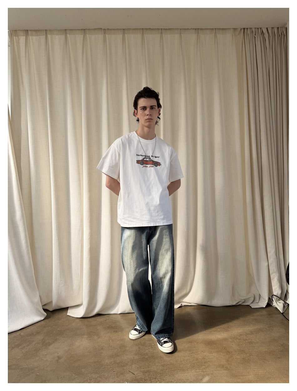 Full-length front view of a model wearing a white car-graphic T-shirt and loose faded jeans.
