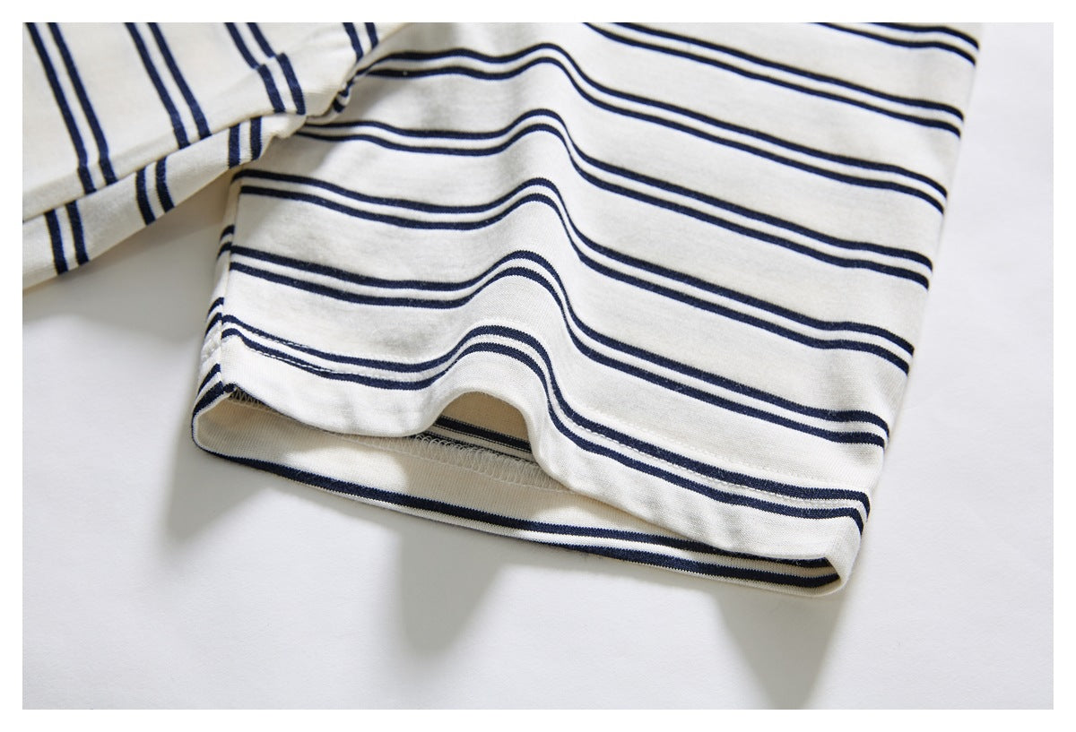 Close-up of an ivory garment sleeve hem with dark navy horizontal stripes.