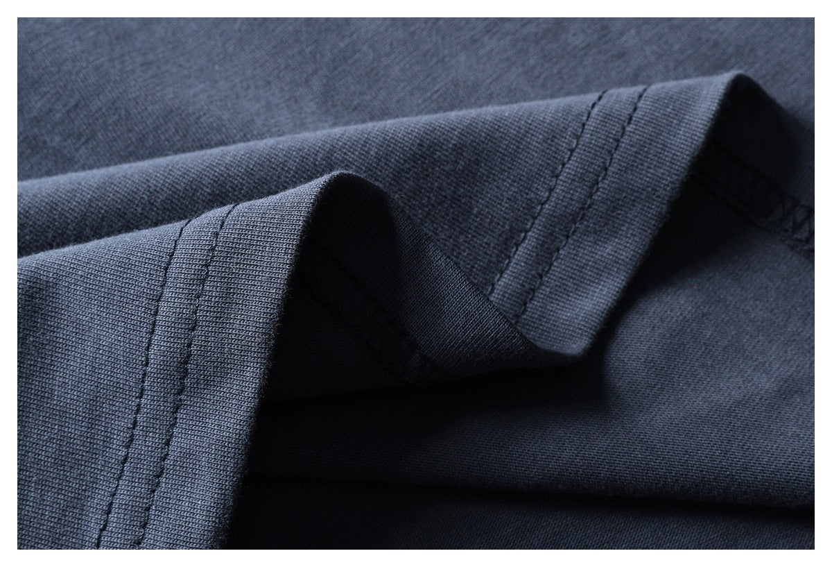 Close-up of dark navy garment fabric folded to show a stitched edge and hem.
