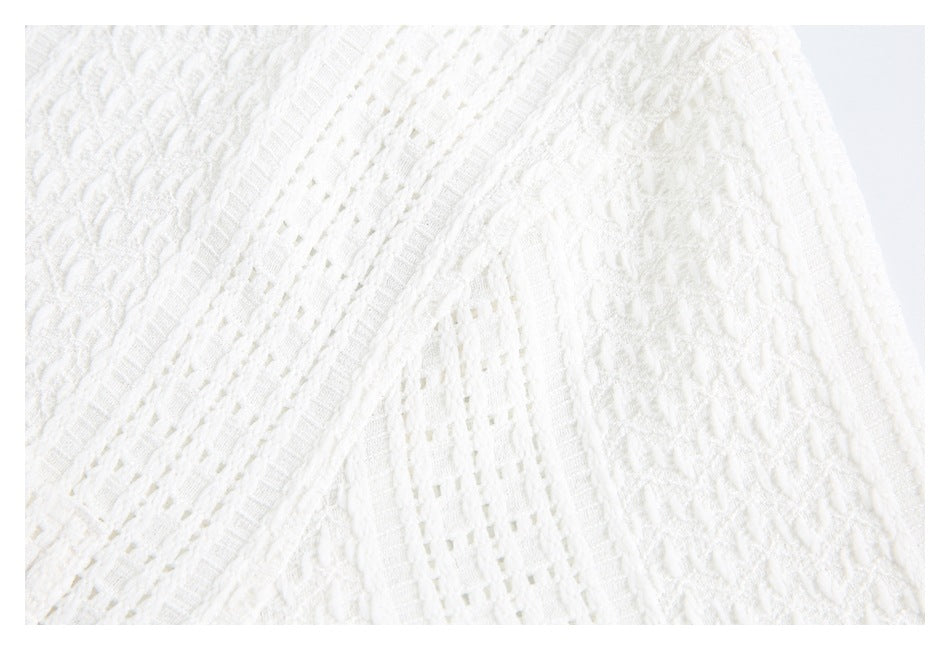 Close-up of white textured knit with alternating openwork bands and a curved seam.