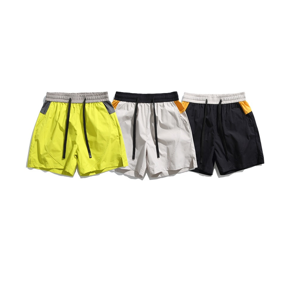 Three pairs of color-block shorts shown from the front: neon yellow, light gray with mustard accents, and black.