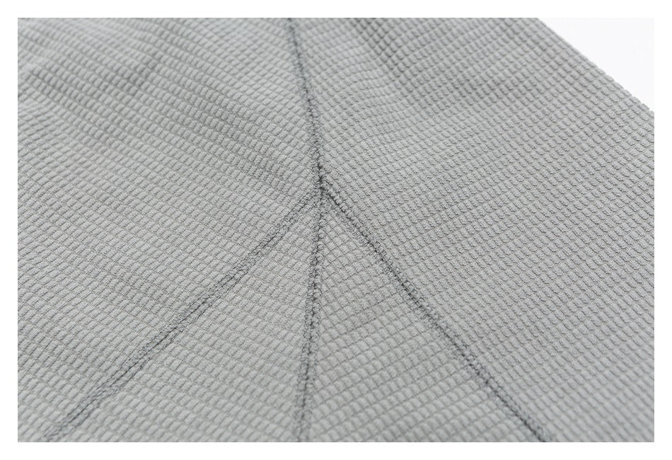 Close-up of gray textured fabric with intersecting stitched seams.