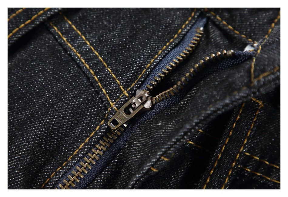 Close-up of a metal zipper and golden stitching on black denim.
