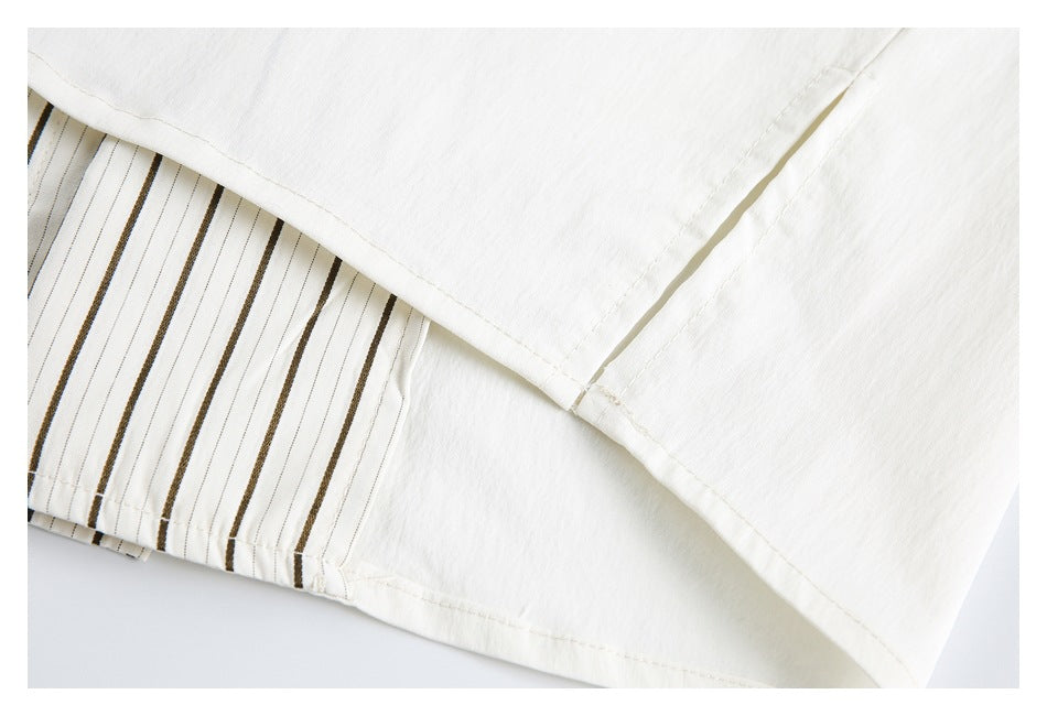 Close-up of a white garment seam beside a panel with narrow dark vertical stripes.