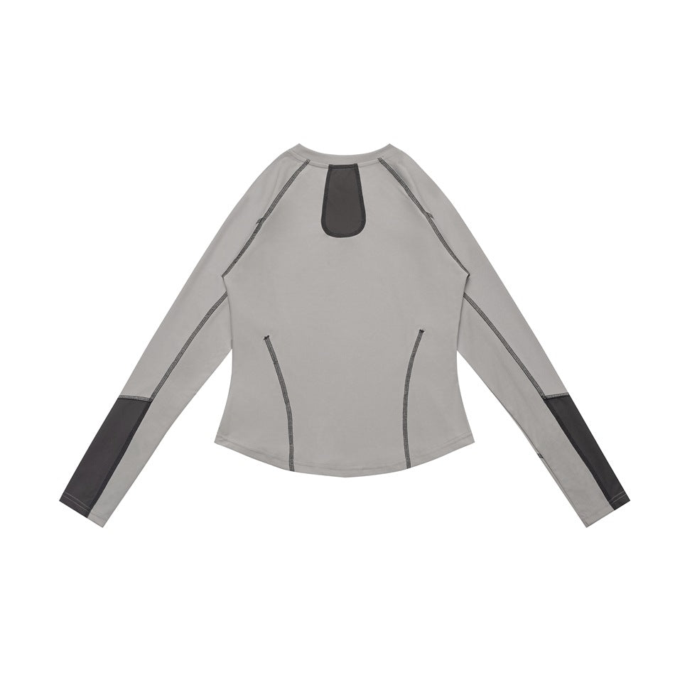 Flat lay of a gray long-sleeve top with dark contrast stitching, sleeve panels, and a dark patch below the back neckline.