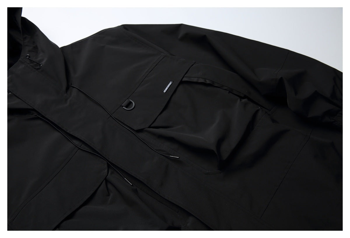 Close-up of the black jacket's front flap pocket, D-ring, hood and covered closure.