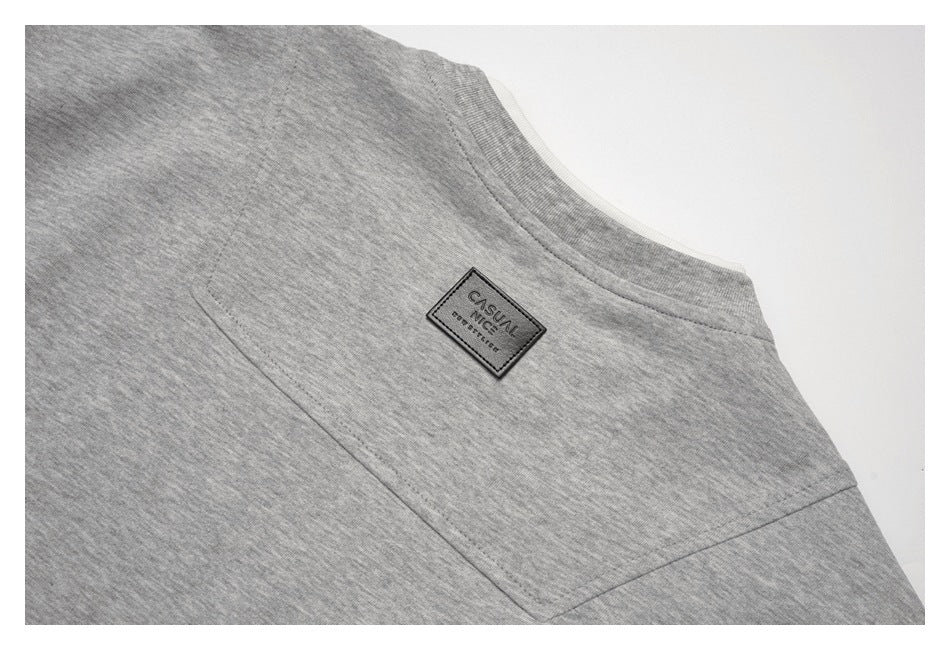 Close-up of a heather-gray garment shoulder seam and neckline with a small sewn rectangular label.