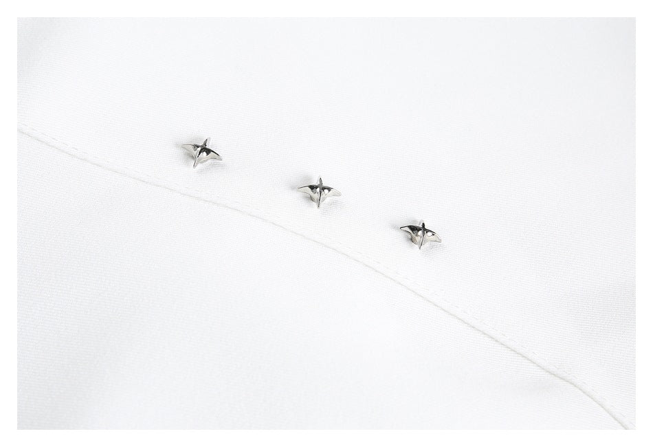 Close-up of three silver star-shaped details along a curved seam on white shirt fabric.