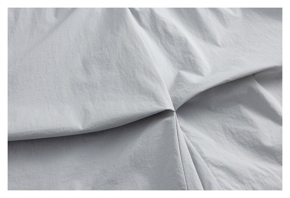 Close-up of overlapping light gray fabric panels and a curved seam on the shorts.