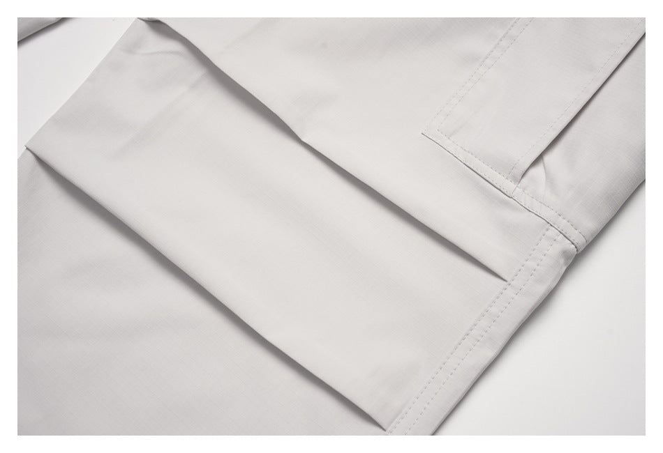 Close-up of an off-white pant leg hem with double stitching and a cargo pocket edge.