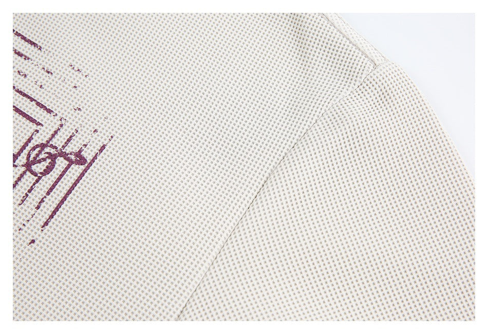 Close-up of the off-white shirt's textured fabric and shoulder seam, with part of a burgundy graphic at the edge.