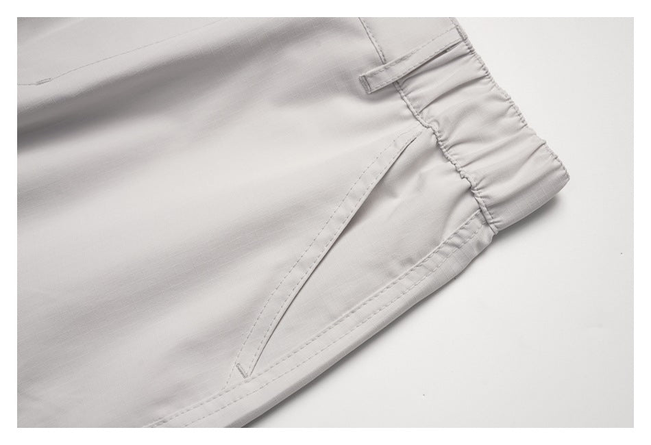 Close-up of off-white pants showing the gathered waistband, belt loop and angled pocket opening.