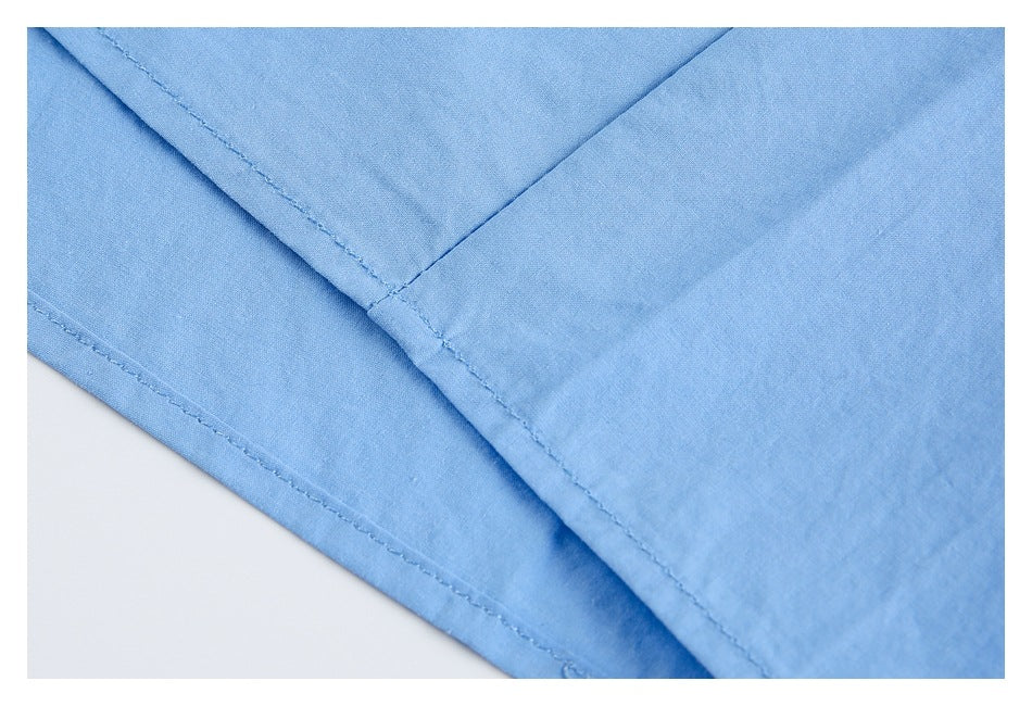 Close-up of overlapping light blue garment panels and stitched seams.