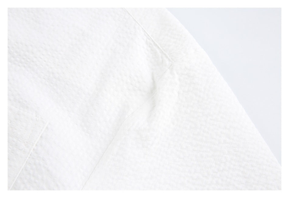 Close-up of the white shirt's sleeve seam and textured surface.