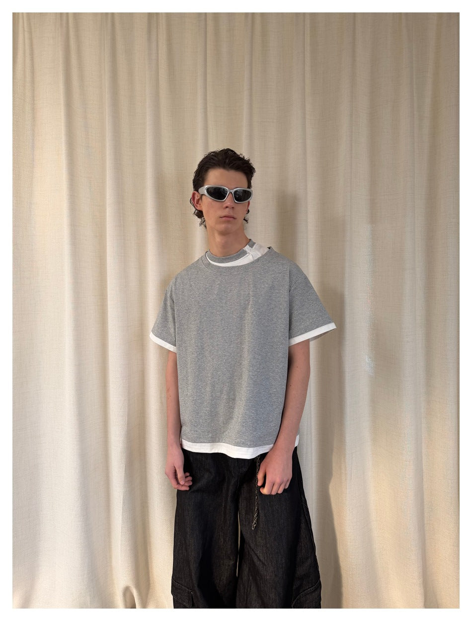 Front view of a model wearing a loose gray T-shirt with white layered trim at the collar, sleeves, and hem.