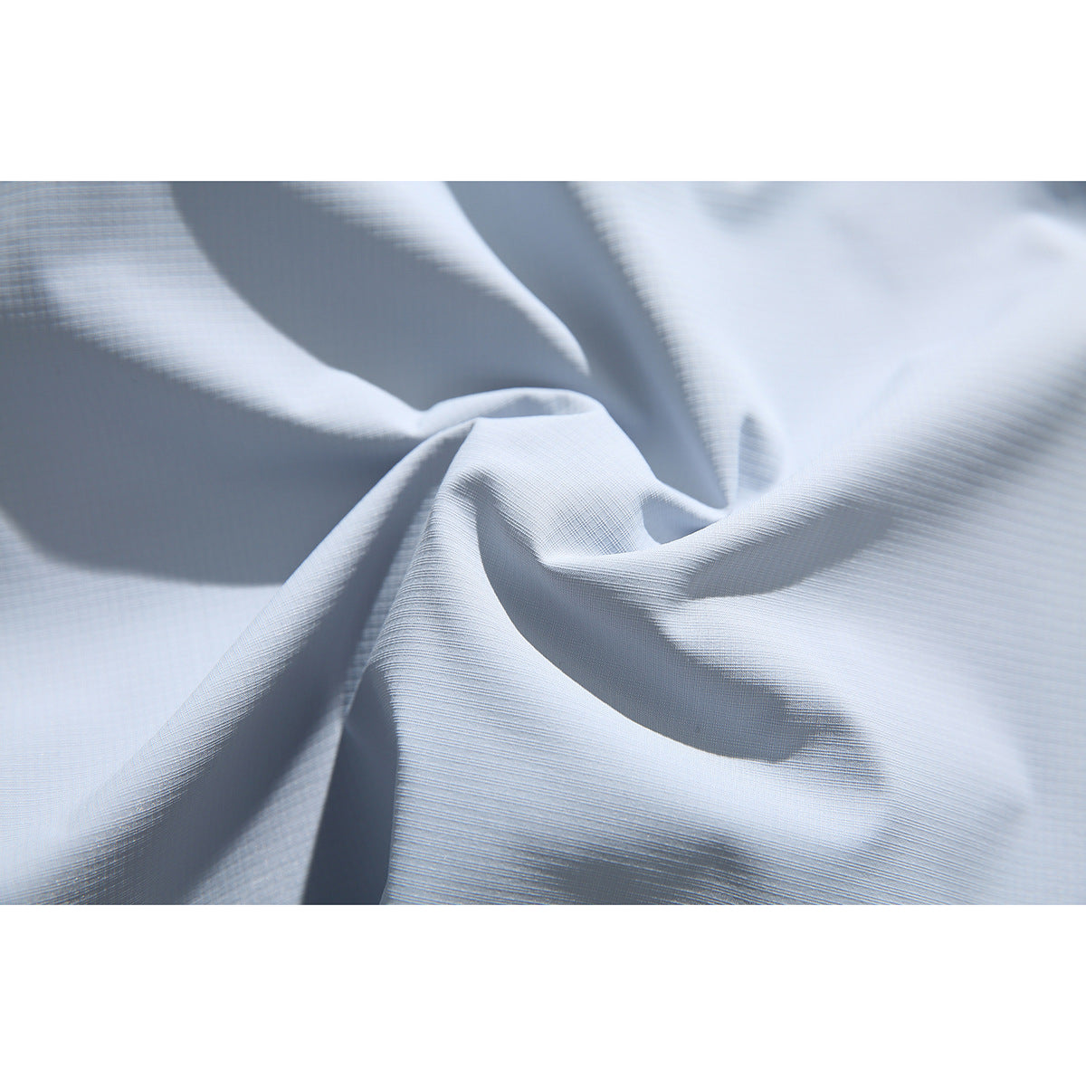 Close-up of pale blue-gray fabric draped to show its fine woven texture.