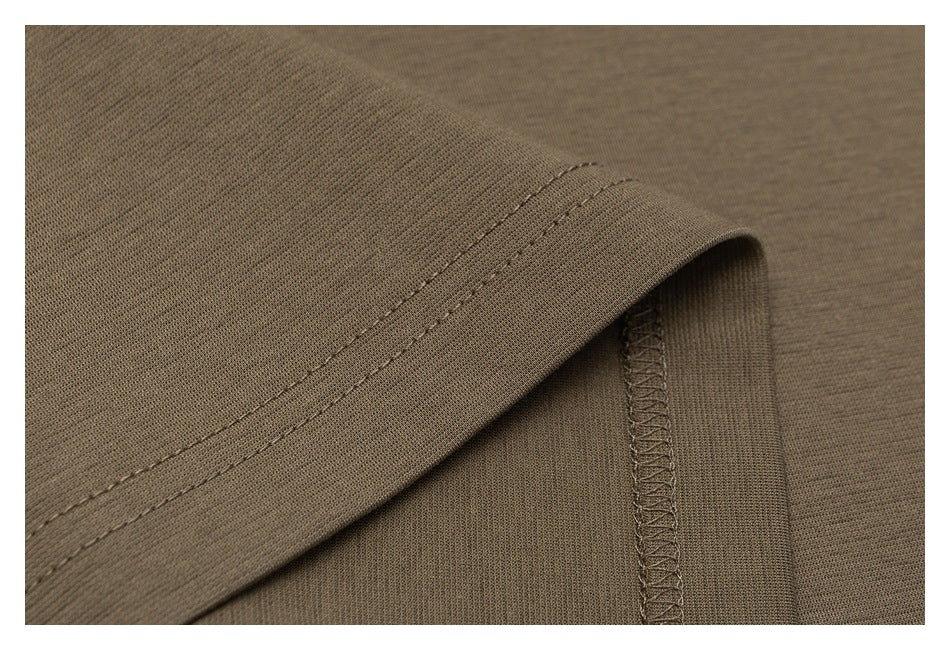 Close-up of a taupe garment hem with double stitching and an overlocked seam.