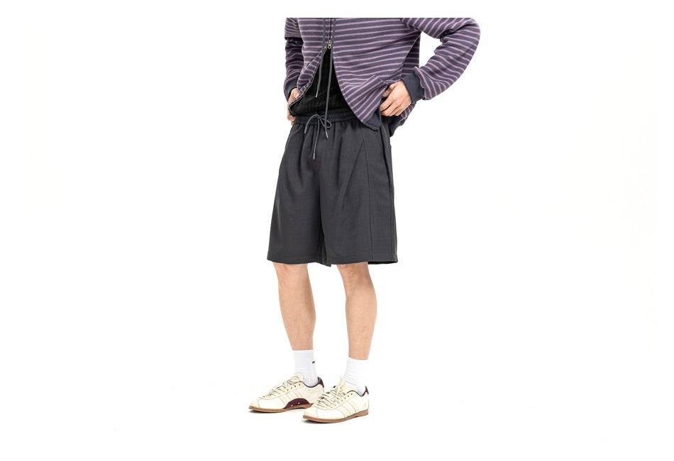 Model wearing loose charcoal drawstring shorts, shown from a slight front angle.