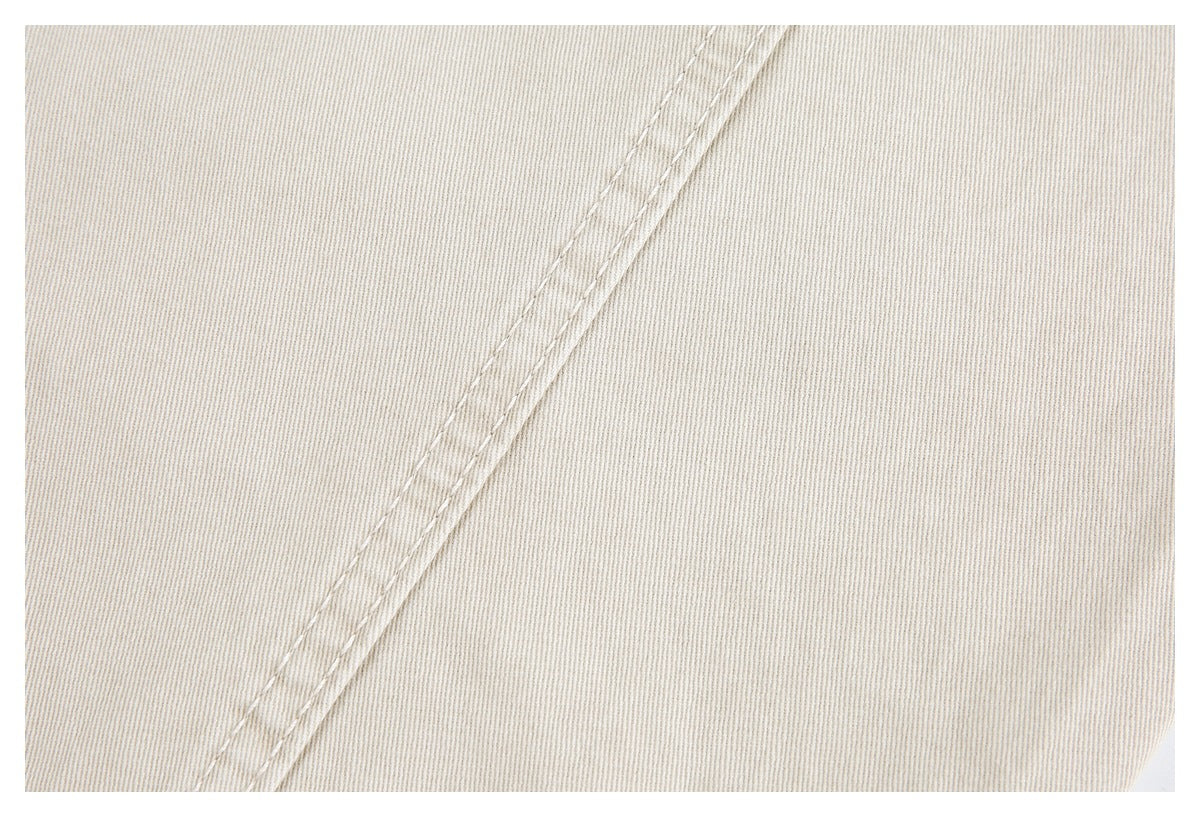 Close-up of light beige fabric with a diagonal double-stitched seam.