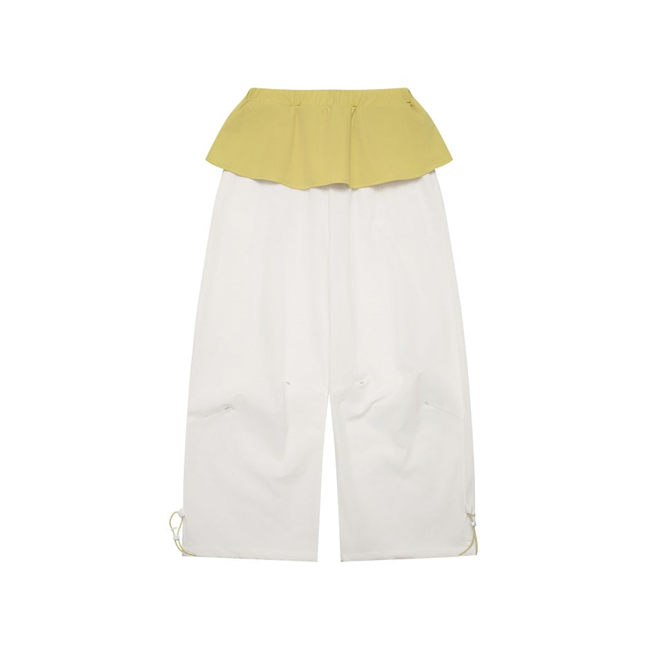 White wide-leg pants with a yellow-green flounce waist panel and hem drawcords, flat lay