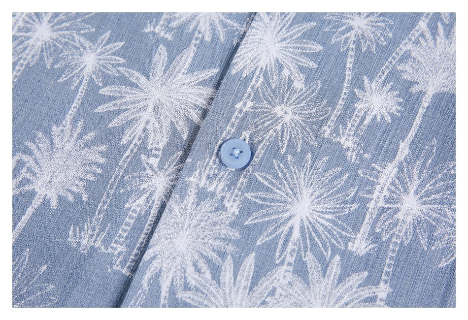 Close-up of a light blue button on fabric patterned with white palm trees.