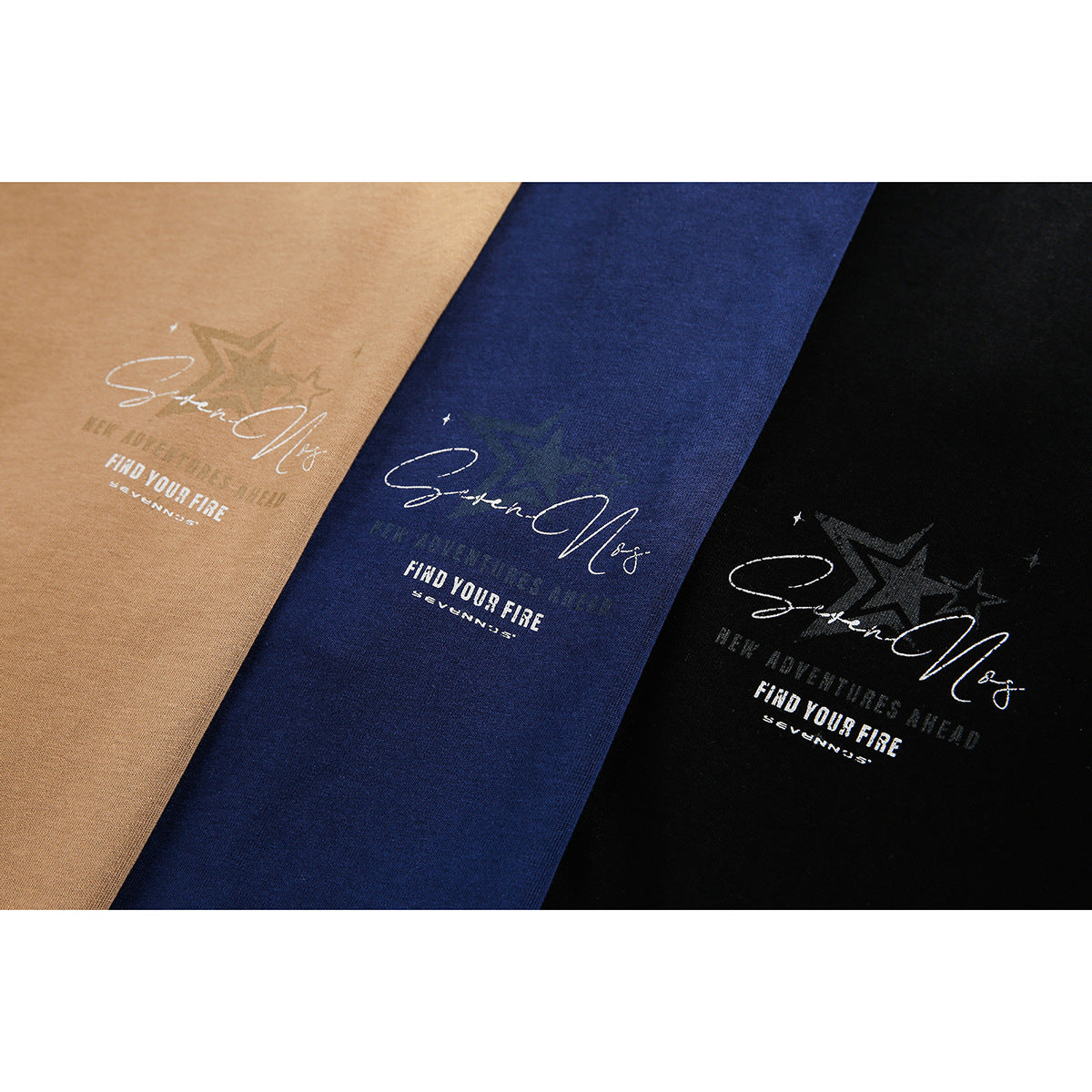Close-up of graphic prints on tan, navy, and black T-shirts, featuring script lettering and star motifs.