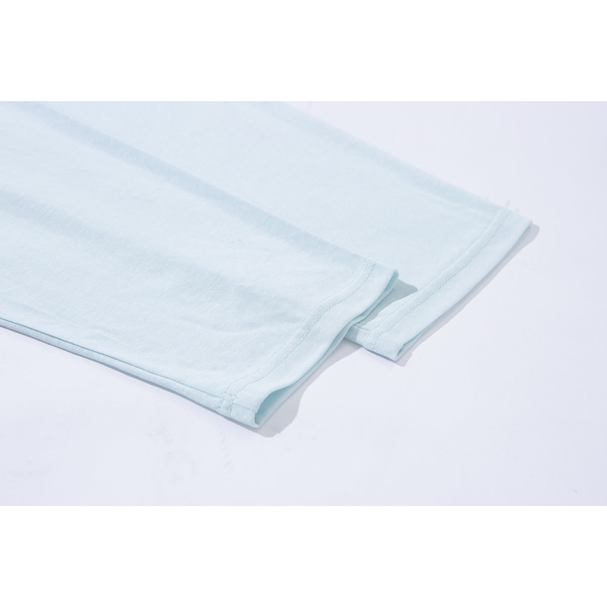 Close-up of the pale blue shirt's sleeve and hem stitching.