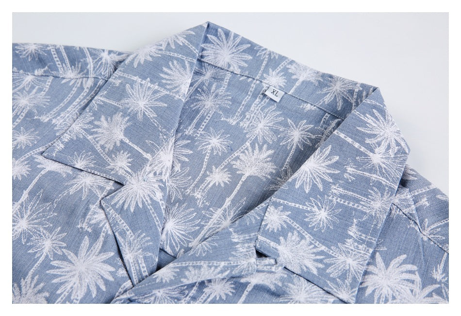 Close view of a blue shirt laid flat, showing its collar, lapels and white palm-tree print.